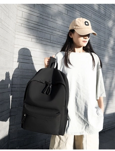 Detail view of a black minimalist oxford backpack featuring dual zippers and durable fabric