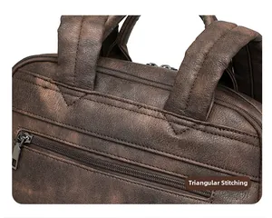 Detail of reinforced triangular stitching and top handle on dark brown PU leather backpack