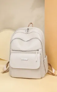 Detail view of beige Oxford fabric backpack featuring multi-layer zippers and metal trim