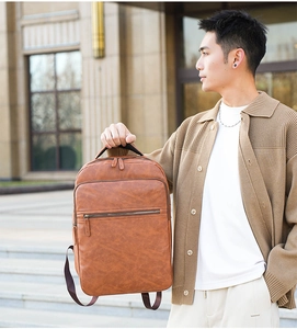 Brown vintage PU leather backpack for men held by model during outdoor commute