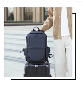 Waterproof black travel backpack secured on a silver rolling suitcase during travel
