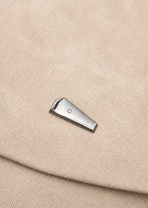 Detail eines beigen Oxford-Rucksacks mit dunkelgrauen geometrischen Metallverzierung
