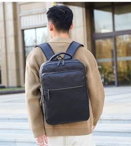 Detailed view of a black pebbled leather laptop backpack worn by a model in outdoor setting