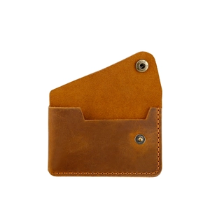Detailed close-up of handmade brown leather wallet with copper button and wax thread stitching