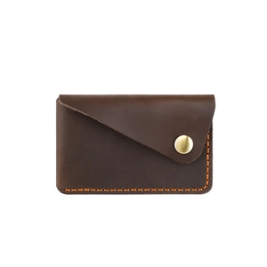 Macro shot of handmade vintage brown leather card holder with contrast orange hand-stitching