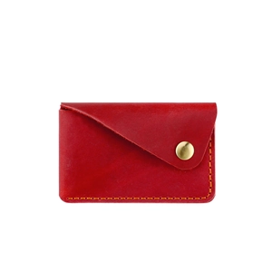 Detail of red handmade leather card holder featuring orange stitching and brass snap button