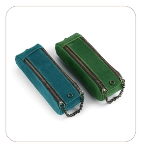 Detail of vintage suede pencil case with dual metal zippers and antique chain accents