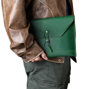 Detail of dark green leather document bag with vintage string closure held under arm