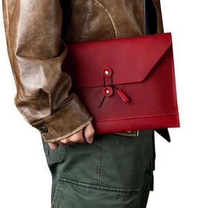 Detail of dark red leather envelope bag with vintage string closure and brass button