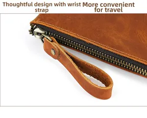 Detail of crazy horse leather wrist strap and metal zipper on brown clutch bag