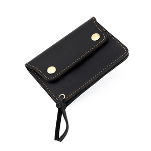 Detail of vintage black leather wallet showing orange contrast stitching and gold snap buttons