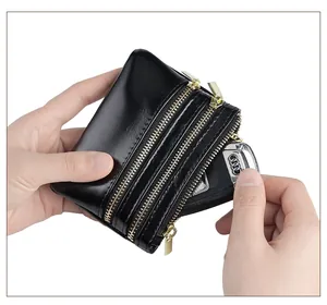 Macro view of black oil wax leather wallet with three gold zippers holding a car key