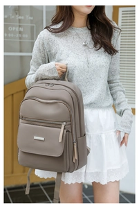 Détail du sac à dos en tissu Oxford taupe avec fermetures éclair et plaque logo métal
