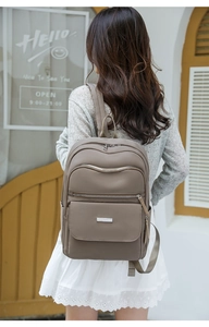 Vue arrière d'un sac à dos en nylon taupe avec plusieurs poches sur une tenue décontractée