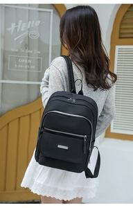 Détail du sac à dos en nylon noir avec compartiments à fermeture éclair et garniture argent