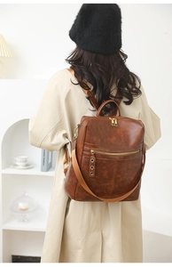 Detail of dark brown vintage faux leather backpack with gold zippers and wide straps