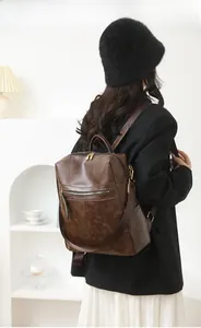 Rear view of model wearing a vintage dark brown PU leather backpack with gold zippers