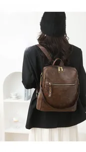 Detail view of brown leather backpack with wide straps and smooth litchi grain texture