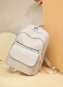 Detail showing the large capacity front pocket and double zipper on the beige backpack