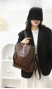 Model wearing dark brown vintage PU leather backpack with gold zippers and wide straps