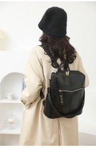 Detail of minimalist black leather backpack with gold zippers and rings on model