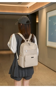 Détail d'un sac à dos en cuir PU crème avec texture litchi et plusieurs poches zippées