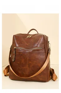 Detail of vintage brown leather backpack showing multi-zipper pockets and wide straps