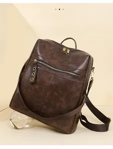 Detail of vintage brown leather backpack with golden zippers and wide canvas straps