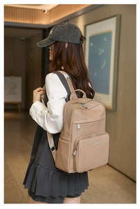 Détail d'un sac à dos beige en cuir grainé avec plusieurs compartiments et poches zippées