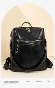 Detail view of the sleek black faux leather backpack with metallic ring charm and top handles