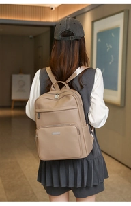 Détail d'un sac à dos élégant en cuir beige avec logo en métal et multiples fermetures