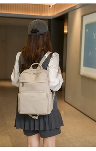 Vue détaillée du dos d'un sac à dos en cuir beige porté par un mannequin en intérieur