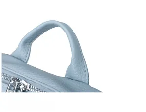 Gros plan sur la poignée en cuir bleu clair à grain litchi et le zip du sac à dos