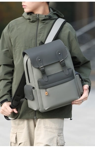 Outdoor shot of a grey color-block backpack with leather straps and multiple pockets