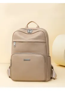 Detail of beige litchi grain leather backpack featuring a front pocket and metal accent