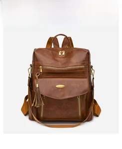 Front detail of vintage brown PU leather backpack with gold zippers and tassel charm