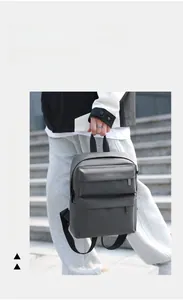 Detail of dark gray faux leather backpack featuring dual front zipper pockets and top handle