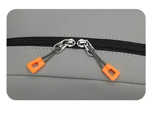 Detail of vintage gray backpack with dual black zippers and vibrant orange pull tabs