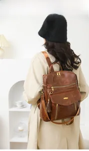 Brown vintage PU leather backpack for women with gold zippers and tassel detail on model