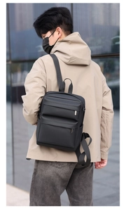 Close-up of a black casual backpack showing textured waterproof fabric and metal D-rings
