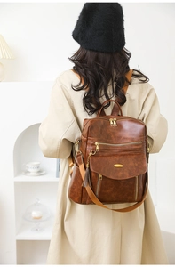 Rear view of brown vintage PU leather backpack with metallic tassel and zipper pockets