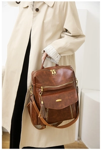 Detail of dark brown vintage PU backpack featuring fringe tassel and gold metal zippers