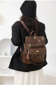 Brown vintage PU leather backpack for women shown with multiple zip pockets on a model