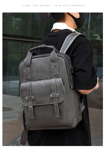 Detail of dark grey PU leather backpack featuring built-in USB charging port and buckles