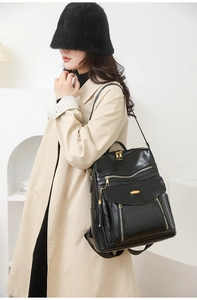 Detail of vintage black PU leather backpack with tassel charms and gold logo plaque