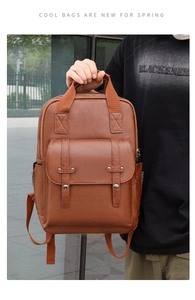 Detail of vintage brown leather backpack showing litchi texture and silver metal hardware