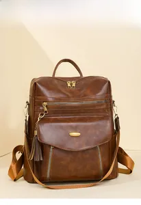 Close-up of brown vintage PU leather backpack with gold zippers and tassel detail