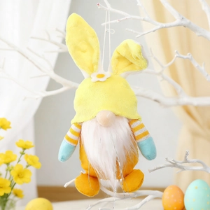 Close-up of a yellow Easter gnome with bunny ears hanging on a white decorative branch