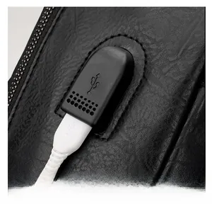 Detail of black leather backpack featuring an integrated USB charging port and cable
