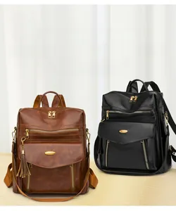 Close-up of brown and black leather backpacks with gold zippers and tassel charms